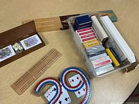 Overall view of lot showing cribbage boards, wooden card/dice box, plastic tub of playing cards
