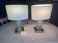 Both lamps lit on table showing shades and glass block bases