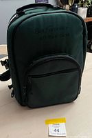 Front view of green picnic backpack showing embroidered text and front pocket