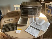 Oven with door closed, accessories and manuals displayed around it