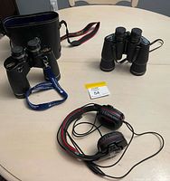 Overview of both binoculars with case and wired headset on table