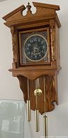 Front view of wall clock showing full case, dial, weights, and pendulum