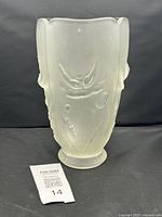 Front angle showing frosted satin crystal glass vase with embossed poppy floral relief and scalloped rim.