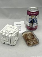 Pair of paperweights shown with a soda can for size reference: the white cube with geometric patterns, and a small glass paperweight with sepia image inside.