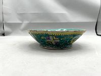 Side view showing the shallow depth and octagonal shape with turquoise interior and exterior decoration including medallions and yellow scalloped border.