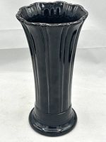 Front angle view of the glossy black Fiestaware flower vase showing vertical fluting and scalloped rim.