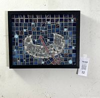 Framed mosaic artwork composed of glass tiles arranged in blue, violet, and gold tones forming a stylized boat and oar design within a black wood frame, hung on a wall.