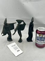 Wide shot of the three cast iron geisha statuettes beside a can for size comparison, showing overall size and shape of each figure.