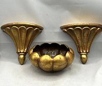 Set of two fluted gilt wall sconces and scalloped bowl in antiqued gold finish.