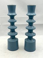 Front view of two blue turned wood candlesticks with stacked rounded segments, showing full height and shape.