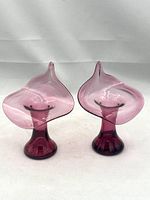 Pair of cranberry-colored Jack-in-the-Pulpit shaped mid-century blown glass vases or candle holders by Pilgrim Glass on a white background, showing their shape and color.
