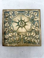 Front view of square Batchelder tile showing Tudor Rose design with blue-green glaze accents