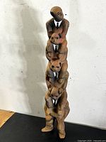 Front view of the 24-inch tall totem-like papier-mâché sculpture of five businessmen stacked and wearing minimalist suits.
