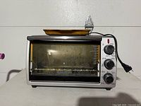 Front view of the Black & Decker toaster oven with the baking tray on top of it.