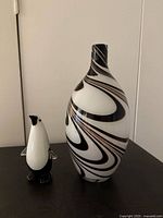 Photo of the black and white swirl patterned decorative vase and black and white penguin figurine from front angle.
