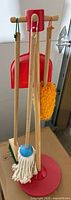 Toy cleaning set showing mop, dustpan and cleaning stand with hanging tools.