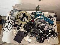 Top view of table with assorted computer cables, power adapters, USB floppy drive, and card readers loosely arranged.