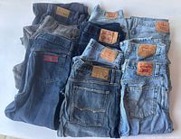 Overview photo of 10 pairs of folded jeans in various colors and brands, mostly Levi's.