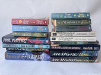 Two stacks of fantasy books showing titles by Brian Jacques, Anne McCaffrey, J.R.R. Tolkien, and Peter S. Beagle.