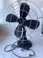 Front view of vintage Hunter electric desk fan with four black metal blades and metal wire cage.