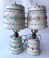 Full view of two Lawnware table lamps with beaded fabric shades and textured white bases, cords visible