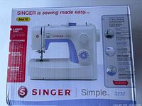 Front view of the box showing Singer Simple 3232 sewing machine image with listed features like 5-minute start, stitch guide, machine intro DVD, anytime support.