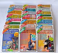 Top view of 20 issues of The Mother Earth News magazines with focus on front covers showing colorful graphics and headlines about sustainable living.