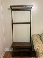 Wooden coat and shoe rack with multiple hooks for coats and a bottom shoe shelf with slats.