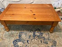 Light-colored wood coffee table with turned legs and drawer, front view