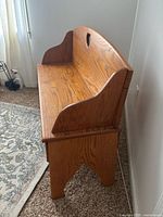 Side view of light wood wooden bench showing curved armrest and sturdy legs