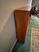 Side view showing the wood grain and minor cracks and wear marks on the side of the shelf unit.