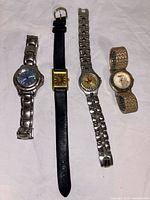 Four women's wristwatches arranged side by side showing different band styles and dial colors.