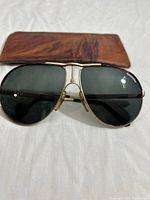 Front view of Carrera aviator sunglasses with leather case in background