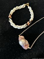 Freshwater pearl bracelet with braided design and multiple bead accents, alongside baroque pearl necklace on silver-tone chain.