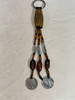 Full view of the handmade keychain showing leather loop, beads, two Buffalo nickels attached, and metal keyring.