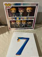 Front view of the BTS Funko Pop Rocks 7-pack collectible figures box and BTS Map of the Soul Version 4 box set with CD and booklet.