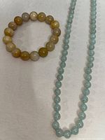 Photo showing both the honey jade bead bracelet in warm tones and the natural green nephrite stone bead necklace.
