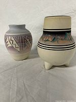 Pair of handmade and painted indigenous ceramic pots on neutral fabric background.