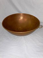 Angled view of the large hammered copper bowl showing the interior and hanging loop.