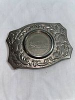 Full view of silver-toned belt buckle with detailed engraving and embedded casino coin showing full design and condition.