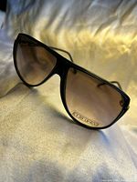 Close-up angle showing front of sunglasses and smoky gradient lenses with UV400 sticker.