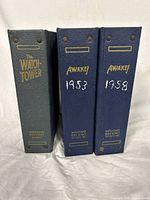 Three hardcover binders standing upright showing spine titles The Watchtower and Awake! years 1953 and 1958