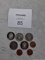 Photo showing eight Canadian coins, mainly silver-tone 50 cent coins and copper-tone 1 cent coins with Canadian Coat of Arms designs.