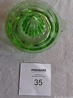 Top view of green glass citrus juicer reamer showing ridged reamer center and pouring spout.