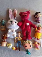 Photo of assorted plush toys, vinyl figures, and action figures arranged on a surface.