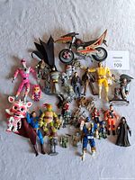 Top-down photo showing full mixed lot of approx. 25 action figures and accessories including Power Rangers motorcycle and various characters.