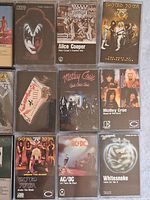 Top view of twelve cassette tapes showing album cover art from bands including KISS, Alice Cooper, Twisted Sister, Mötley Crüe, AC/DC, Whitesnake, and Van Halen.