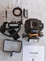 Wasp 4K action camera next to clear waterproof case, black frame mount, and mounting hardware on white textured surface.