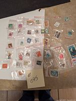 Overview of 34 assorted postage stamps from various countries, individually bagged in small plastic bags.