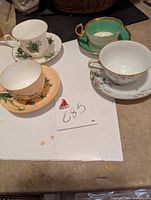 Photo showing full set of 4 assorted tea cups and saucers on a table with lot number 085
